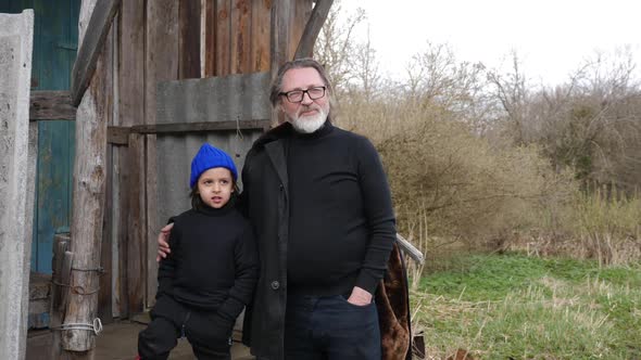 Grandson a Child in a Blue Knitted Hat Stands with His Grandfather