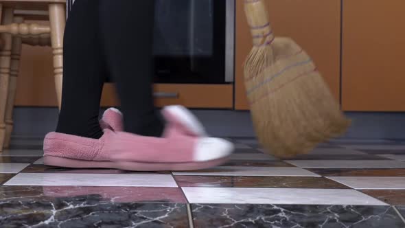 Young Girl Sweeps the Floor in the Kitchen with an Ordinary Broom in Slow Mo