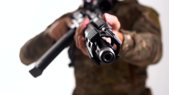 Man in combat camouflage and body armor is aiming a modern assault rifle at the camera