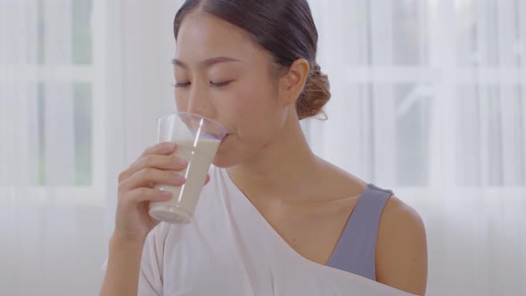 Healthy Young Asian woman Drinking milk with calcium for strong bone at home