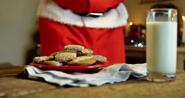 Mid section of santa claus having sweet food