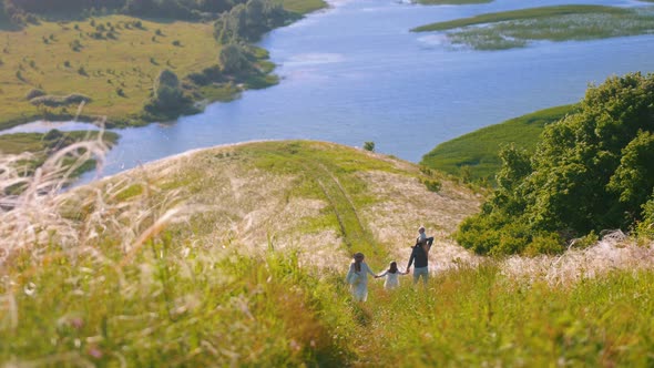 Young Happy Family Walking Down the Hill To the River