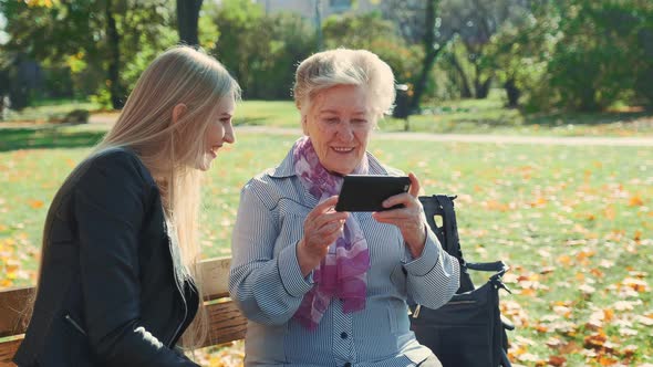 Elder Grandmother Showing Her Granddaughter Photos on Smartphone