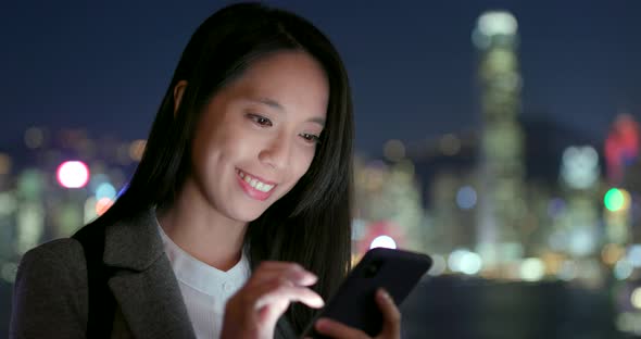Businesswoman use of cellphone in city at night