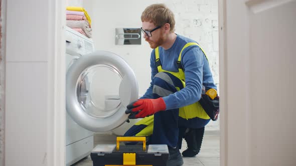 Repairman with Toolbox Near Washing Machine in Bathroom