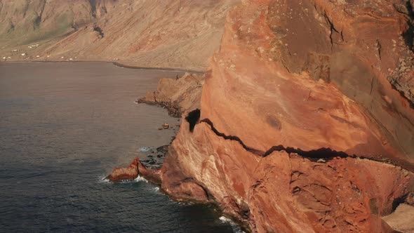 Aerial dolly over old abandoned coastal road cut between the red rocks