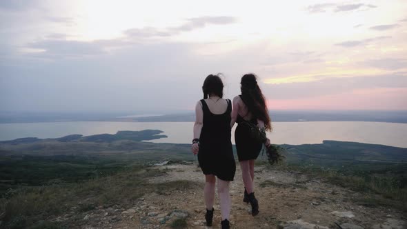 Two Hippie Girls Run Down the Mountainside in Black Dresses