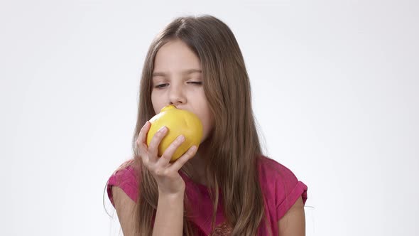 Girl with an Apple. Little Girl Eats a Big Yellow Apple on a White Background.