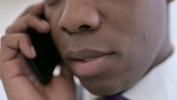 Close Up of African Man Talking on Smartphone in Office 