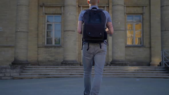 A Back Viev of a Young Photographer Who Is Approaching an Old Church with an Expensive Digital