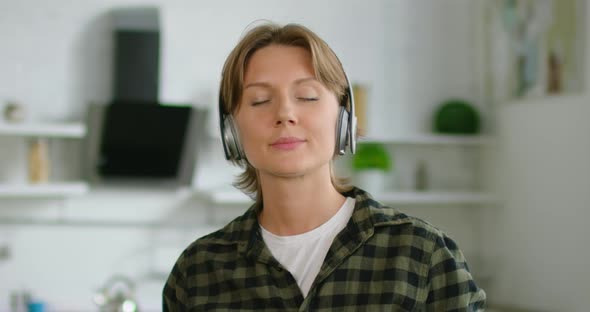 Woman Is Listening Music in Wireless Headset in Kitchen