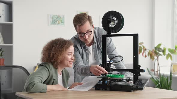 3D Printing Models at Home Smiling Girl with Young Guy are Watching Project for 3D Printer Sitting