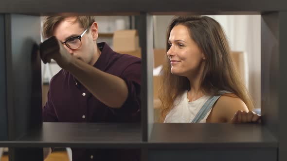 Portrait of Happy Young Family Assembling New Black Wooden Bookshelf