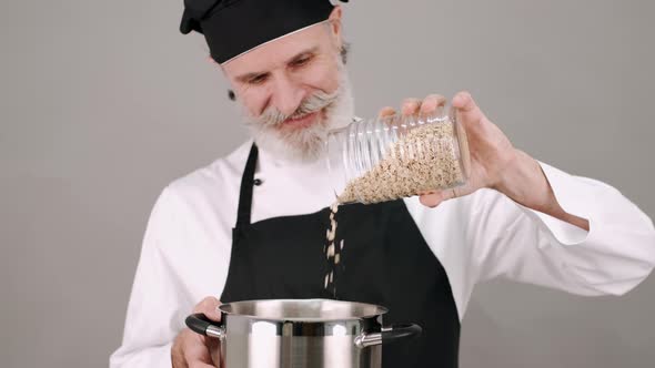 Middle Aged Chef Man Pouring Cereals on Grey Background