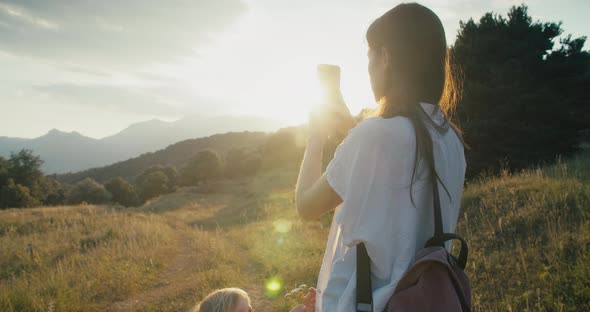 Woman Make Photo of Daughter Using Smartphone on Mountain Summer Travel