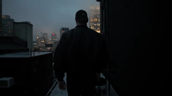 Back View of Man Walking on the Rooftop in New York City at Night