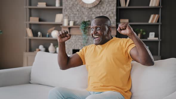 Senior Football Fan African American Man Bachelor Sit on Cozy Sofa in Apartment Watch TV Sport