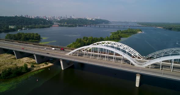 Aerial top view of automobile and railroad Darnitsky bridge across Dnieper river from above.