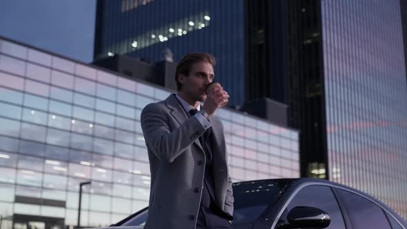 Portrait of a Cheerful Businessman Standing Near a Black Car Enjoying a Cup of Coffee Top Manager in