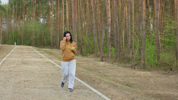 Caucasian Girl Puts on Headphones on a Run