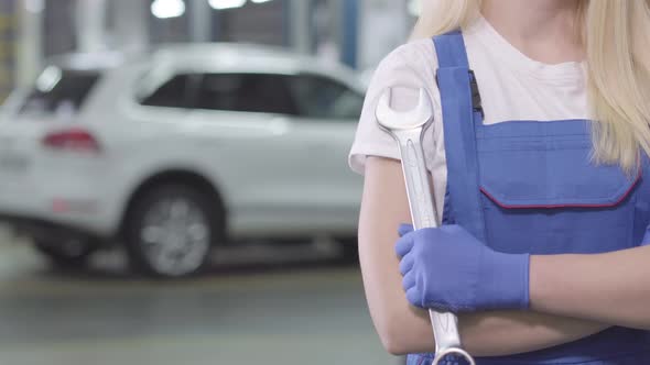 Unrecognizable Caucasian Woman in Workrobe and Gloves Crossing Hands Holding Wrench. Young Female