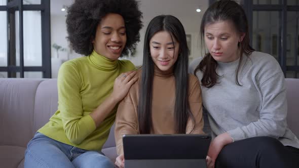 Three Beautiful Cheerful Young Women Surfing Social Media on Tablet Talking and Smiling in Slow