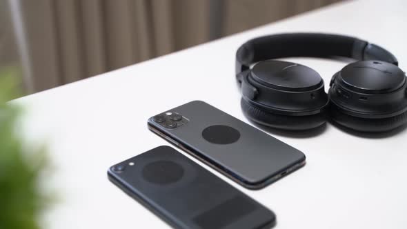 close up video of two dark smartphone and headphones on a white table