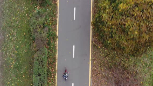 Aerial view Child riding bicycle in autumn park. Active sport family leisure