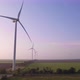 Windmills in a green field at sunset. Wind farm with turbine cables for wind energy. - VideoHive Item for Sale