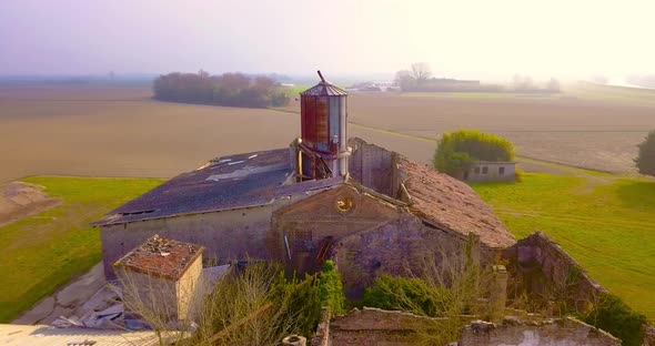 Birds Fly Over Tower on Abandoned Farmhouse at Village Edge