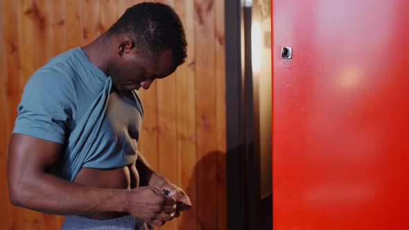 Africanamerican Athletic Young Man Tying Up His Shorts in the Locker Room