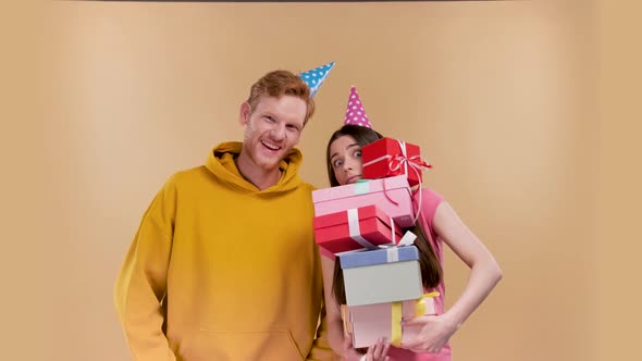 Funny Woman Holding a Huge Amount of Gifts That a Man Gave Her Isolated Over Beige Background