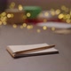 Orbit Shot of Man Move Notepad with Pencil on Walnut Wood Table with Christmas Lights on Background - VideoHive Item for Sale
