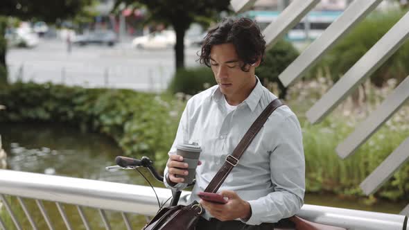 Asian Businessman Sitting Near Bike and Using Mobile