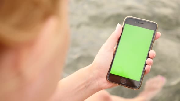 NICE, FRANCE - JULY 2017 Green screen smart phone in woman hands at the beach slow motion video