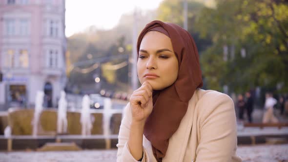 A Young Beautiful Muslim Woman Thinks About Something in a Street in an Urban Area