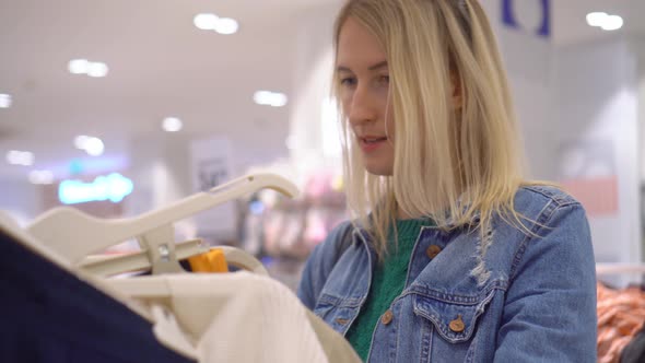 Beautiful woman chooses and buys clothes in shopping mall