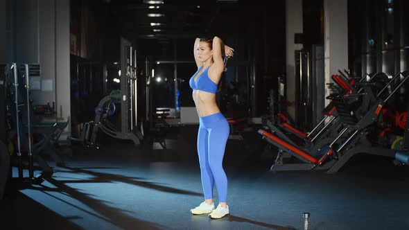 Female Athlete in Sportswear Working Out and Training Her Arms and Shoulders With Dumbbell in Gym