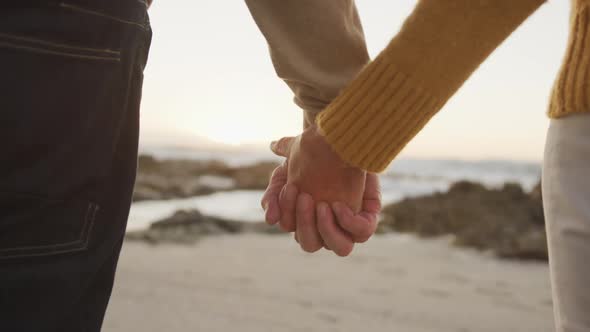 Close up view of senior couple holding hands at beach