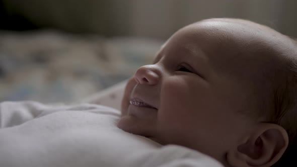 Close Up Portrait Of A Cheerful Baby Lying In Bed Smiling