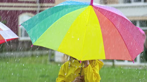 Cute Girl in Yellow Raincoat Jumping in Rain