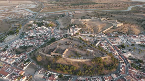 Vast landscape aerial descending shot of hilltop Castelo de Castro Marim and fort of sao sebastiao.