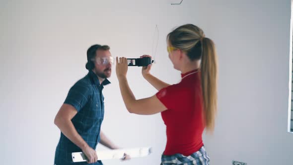 Happy Girl Shoots Boyfriend Dancing with Level Tool in Flat