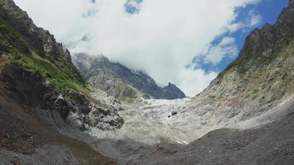 Aerial View of a Mountain Glacier on a Sunny Summer Day Against the Backdrop of a Cloudy Sky