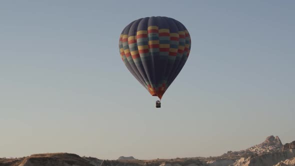 Large Hot Air Balloon with Tourists Flies Over Hills