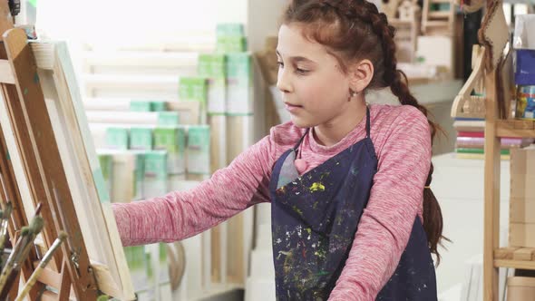 Beautiful Little Girl Painting on the Easel Using Oil Paints at the Art Studio