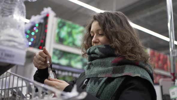 Curlyhaired Woman Chooses Ornaments for Christmas Tree