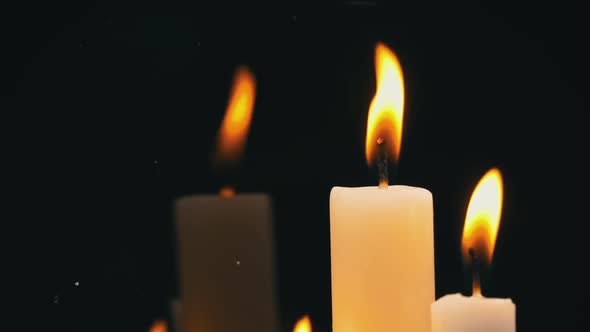 White Paraffin Candles with a Yellow Tint Burn on Black Background in Reflection