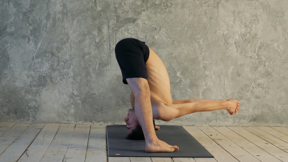 Sporty muscular young yogi man doing Wide-Legged Forward