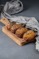 Whole baked potatoes with thyme on a wooden board on a gray ston - PhotoDune Item for Sale